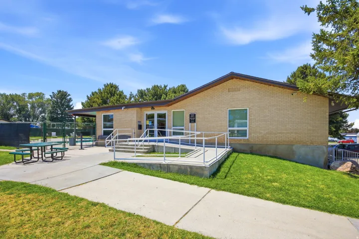 Brick exterior building with a prominent entrance featuring a ramp and stairs with metal railings