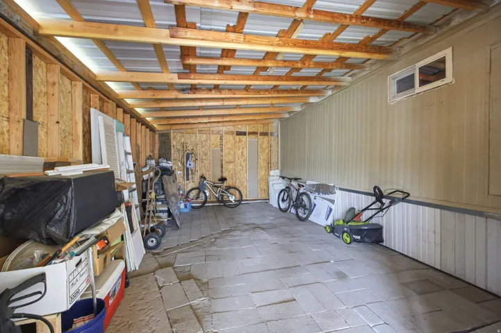 Spacious covered outdoor area featuring exposed wood ceiling joists and a corrugated metal roof