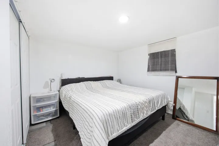 Bedroom featuring a window with horizontal blinds, overhead lighting, and wall-to-wall carpeting