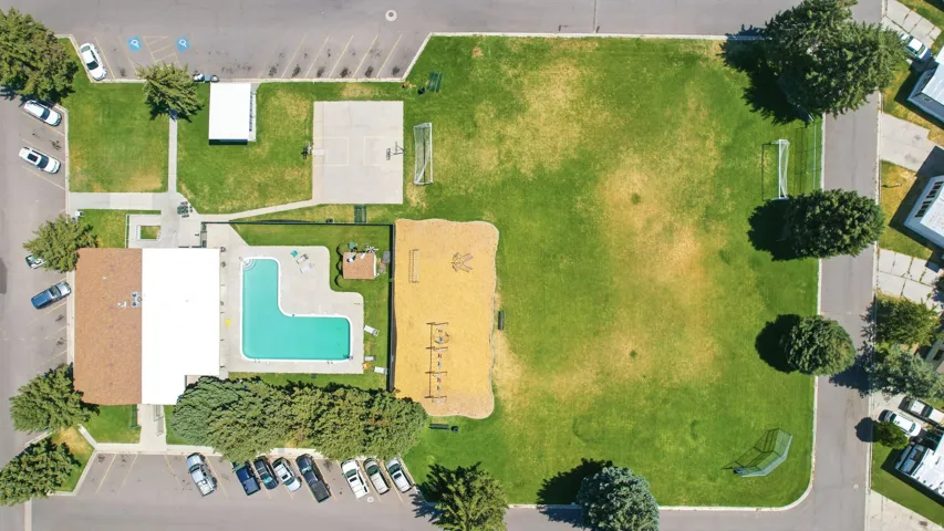 Community amenities featuring a large outdoor swimming pool, extensive green spaces, a children's play area, a basketball court, and soccer goals