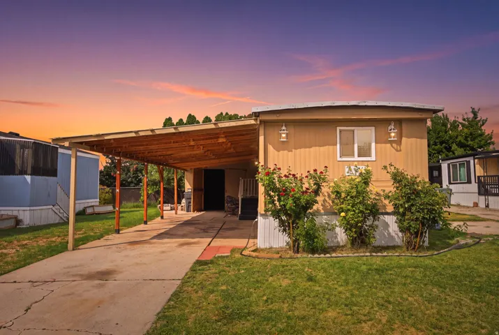 Exterior featuring tan siding, a covered carport, and a concrete driveway