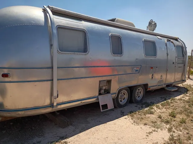 Aluminum-clad trailer featuring multiple windows, a side-mounted awning, and dual axles