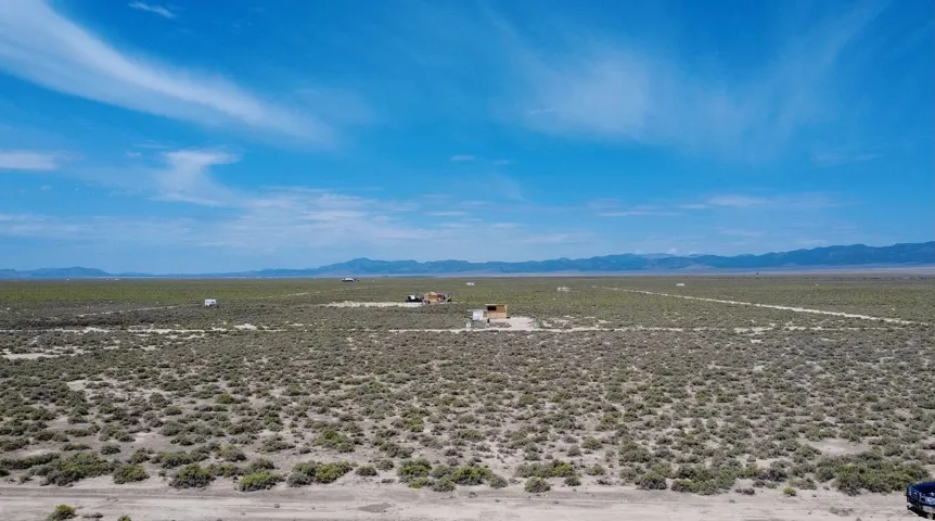 Expansive undeveloped land featuring natural brush vegetation and distant mountain ranges