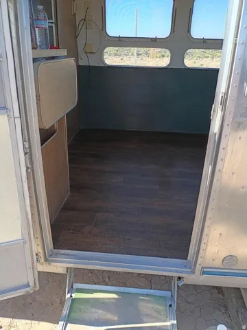 Interior featuring wood-finish flooring, a wall-mounted fold-down table, built-in cabinetry, curved windows, and aluminum-paneled walls