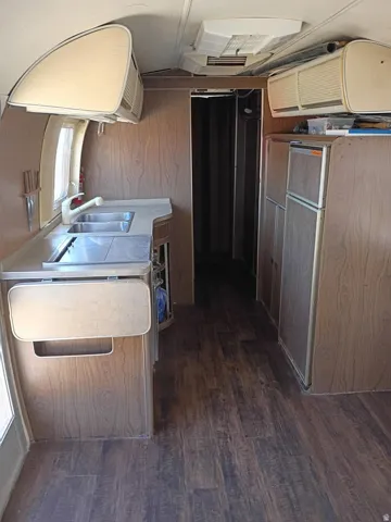 Compact kitchen area featuring wood-finish flooring and wall panels
