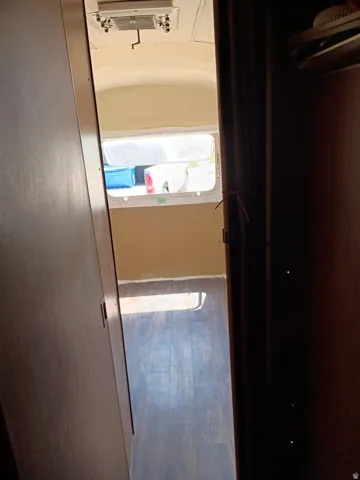 Interior space featuring wood-finish flooring, a window providing natural light, and a built-in ceiling ventilation unit