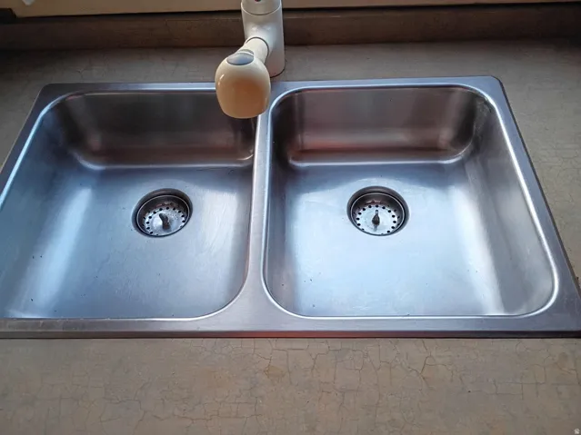 Double-basin stainless steel sink with a single-handle faucet, integrated into a countertop