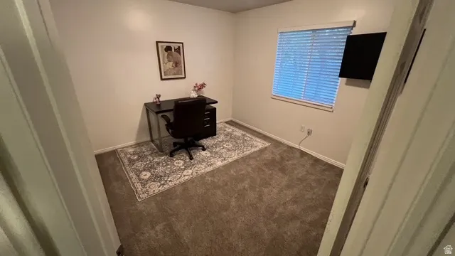 Carpeted room featuring a window with blinds, white baseboards, and a wall-mounted screen