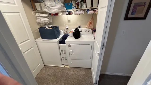 Dedicated laundry closet featuring a washer and dryer, built-in shelving, and carpet flooring