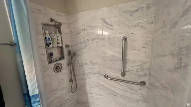 Shower stall featuring a light-toned, variegated wall surface