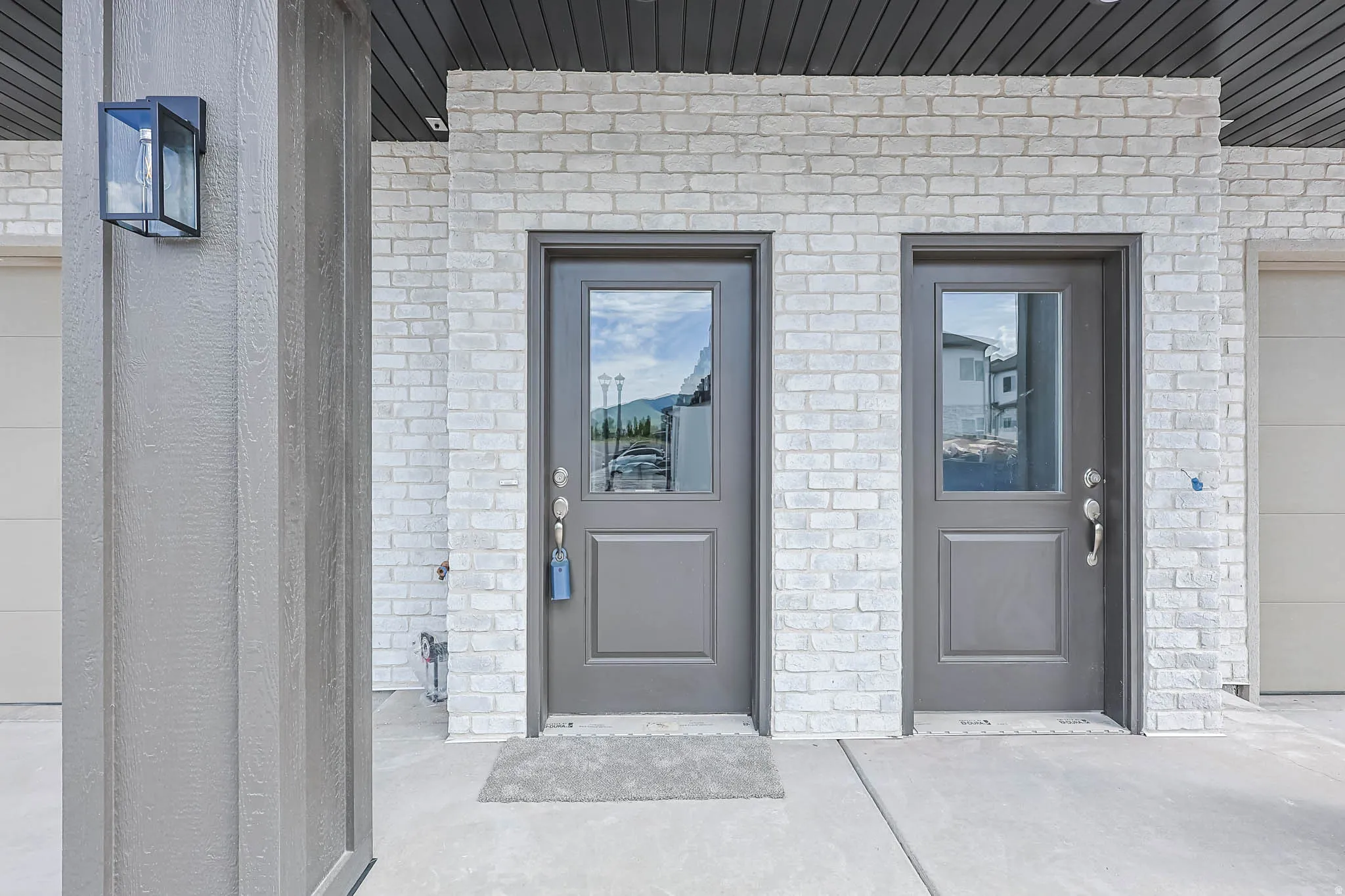 Two panel-style entry doors with upper glass inserts, set against a white brick facade