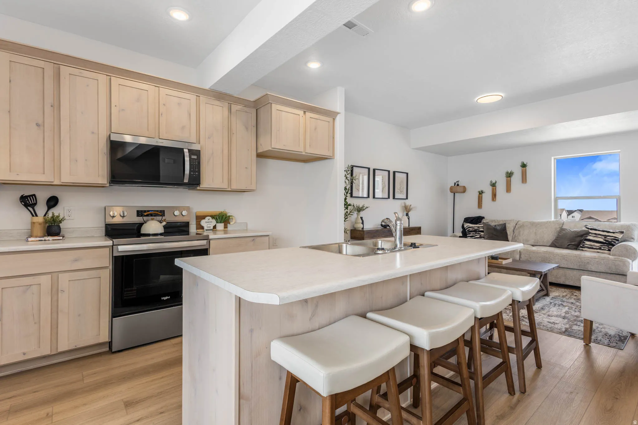 Kitchen featuring light wood-finish cabinetry, stainless steel appliances, a white countertop, recessed lighting, and wood-finish flooring