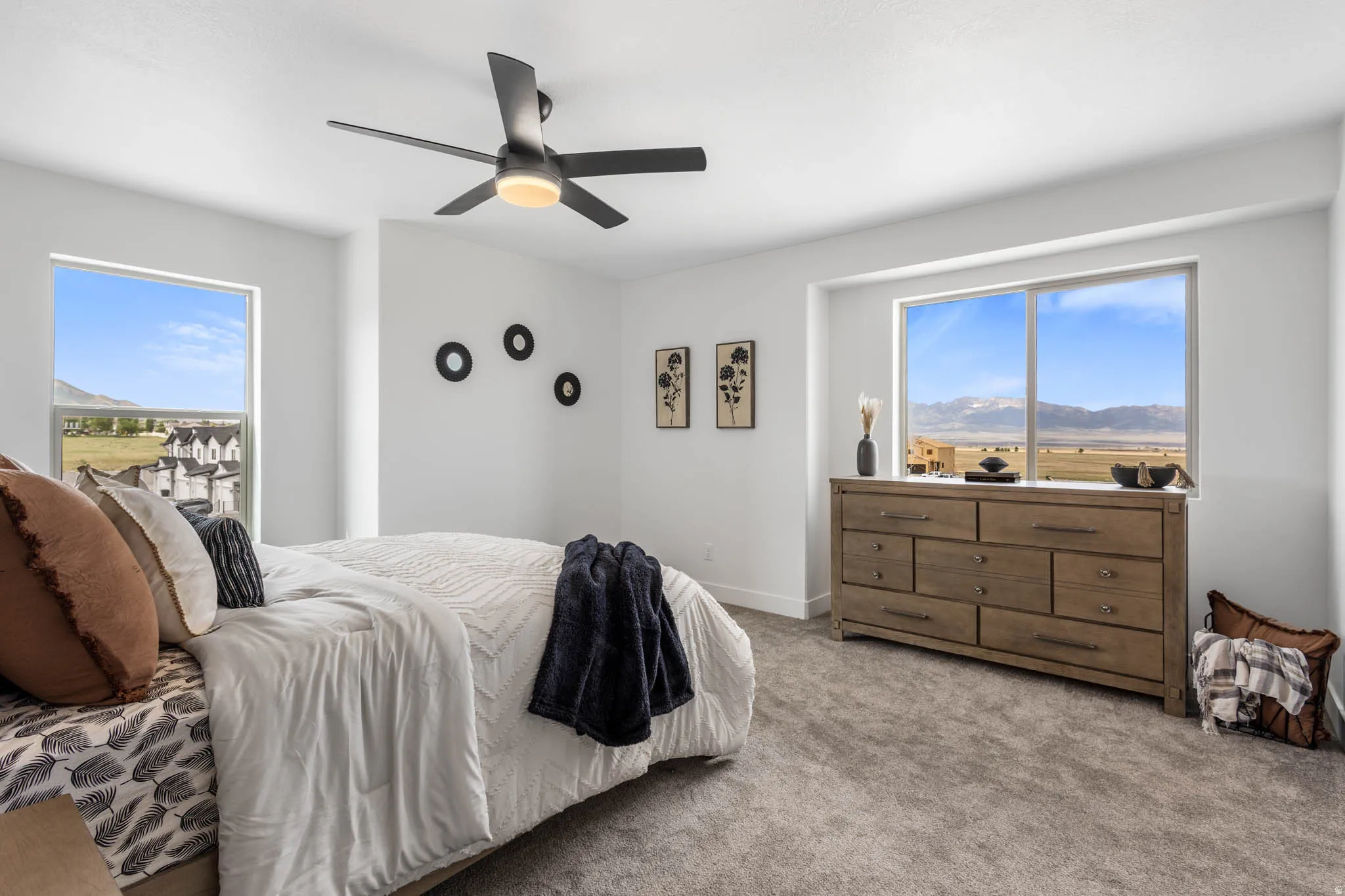 Bedroom featuring large windows, neutral-toned carpeting, white walls, and a contemporary ceiling fan with integrated lighting