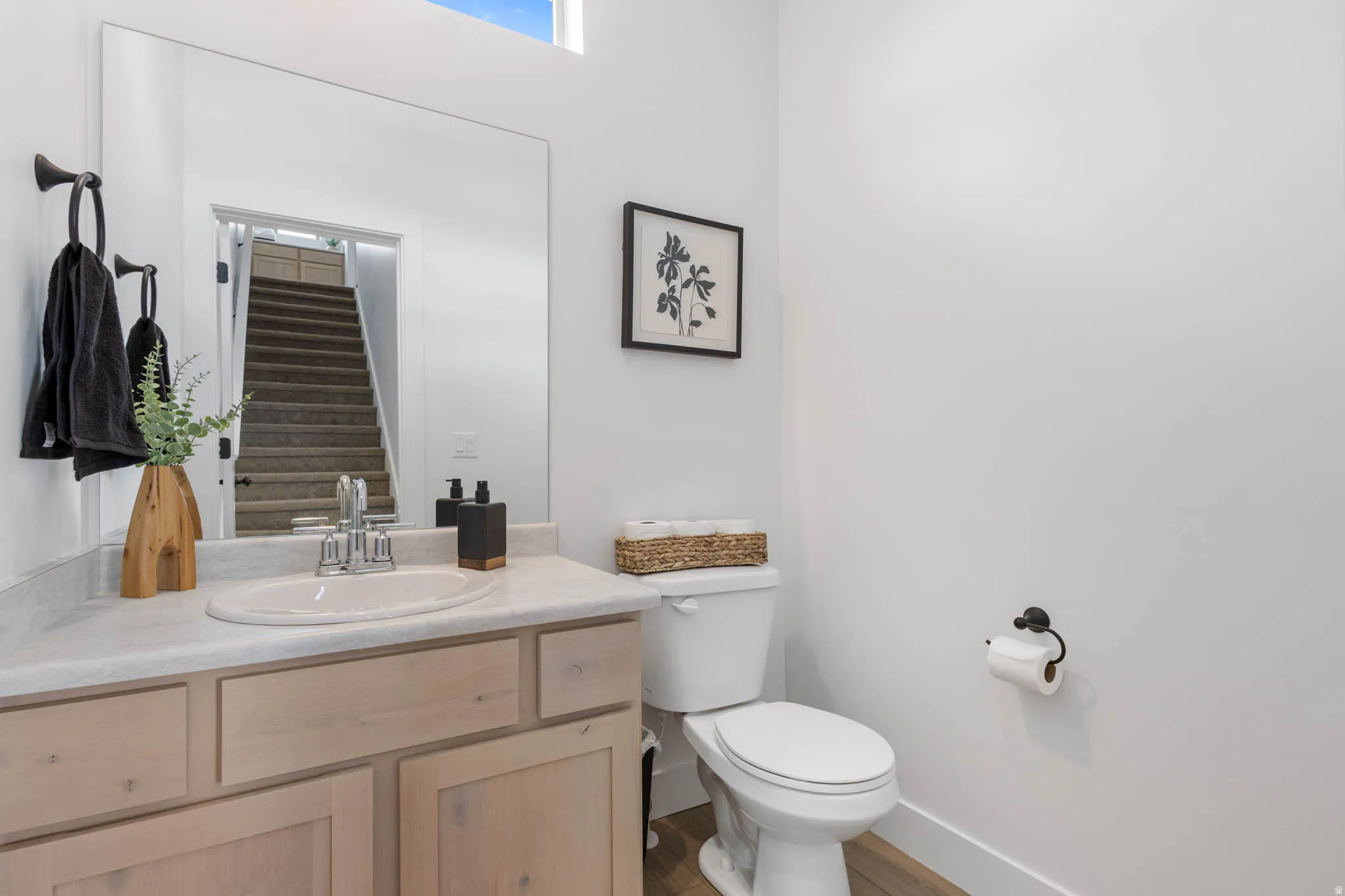 Bathroom vanity featuring a light-toned wood-finish cabinet with a light countertop, undermount sink, and chrome faucet