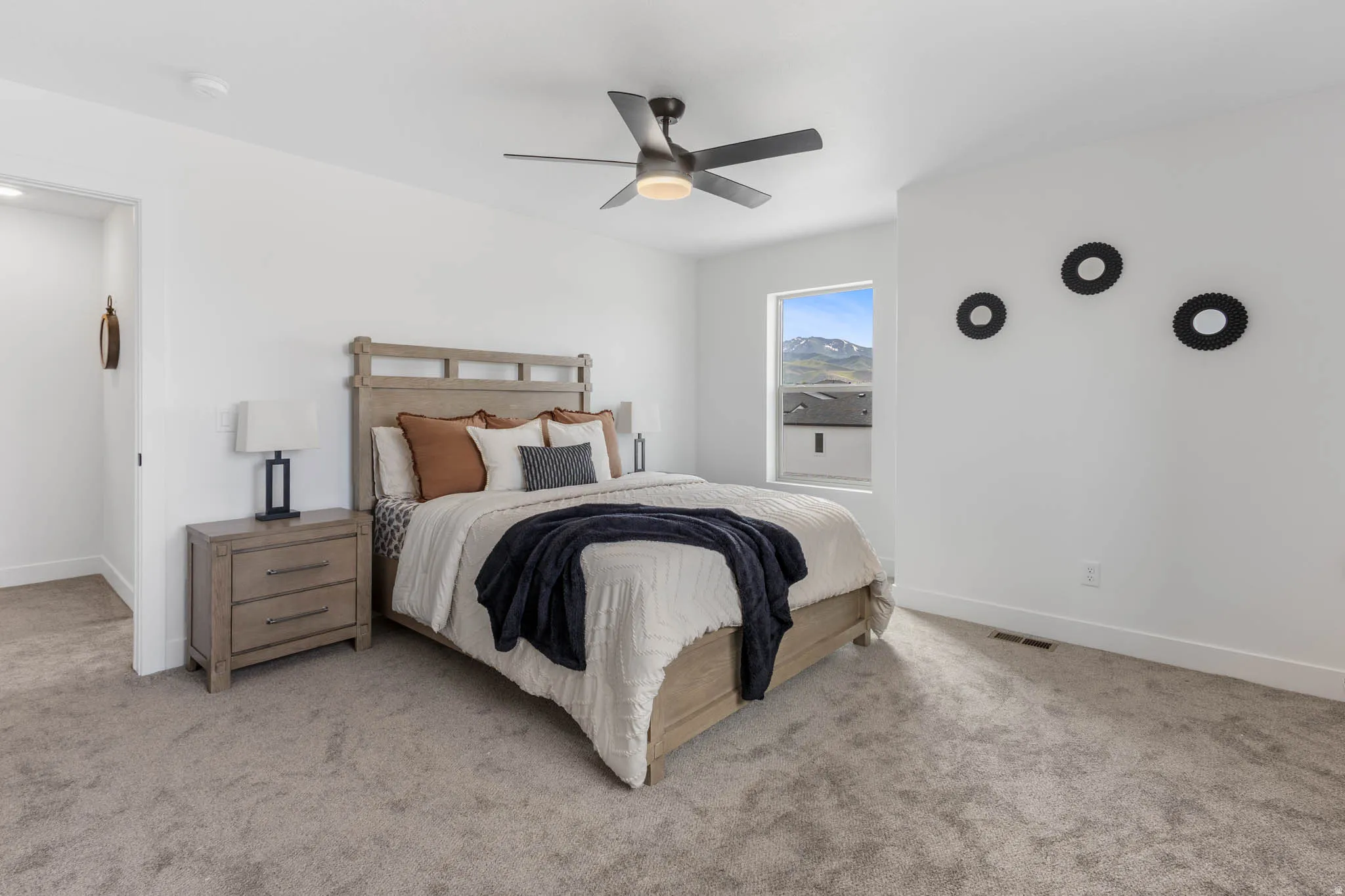 Carpeted bedroom featuring a ceiling fan with integrated lighting, a window with mountain scenery, and white walls