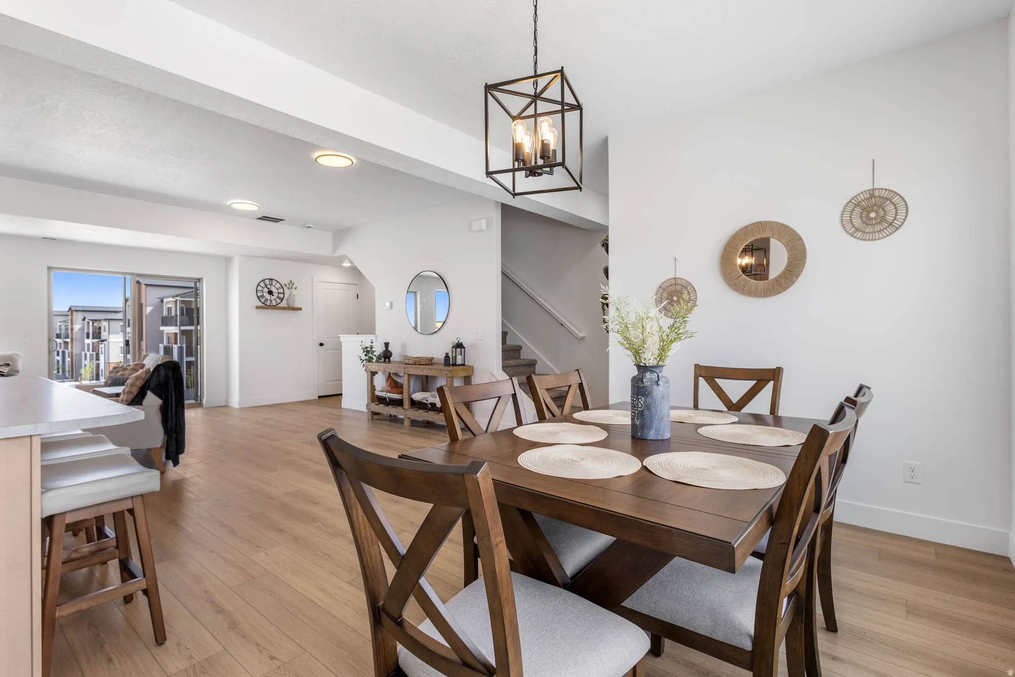 Open-concept dining area featuring a contemporary linear chandelier and light wood-finish flooring