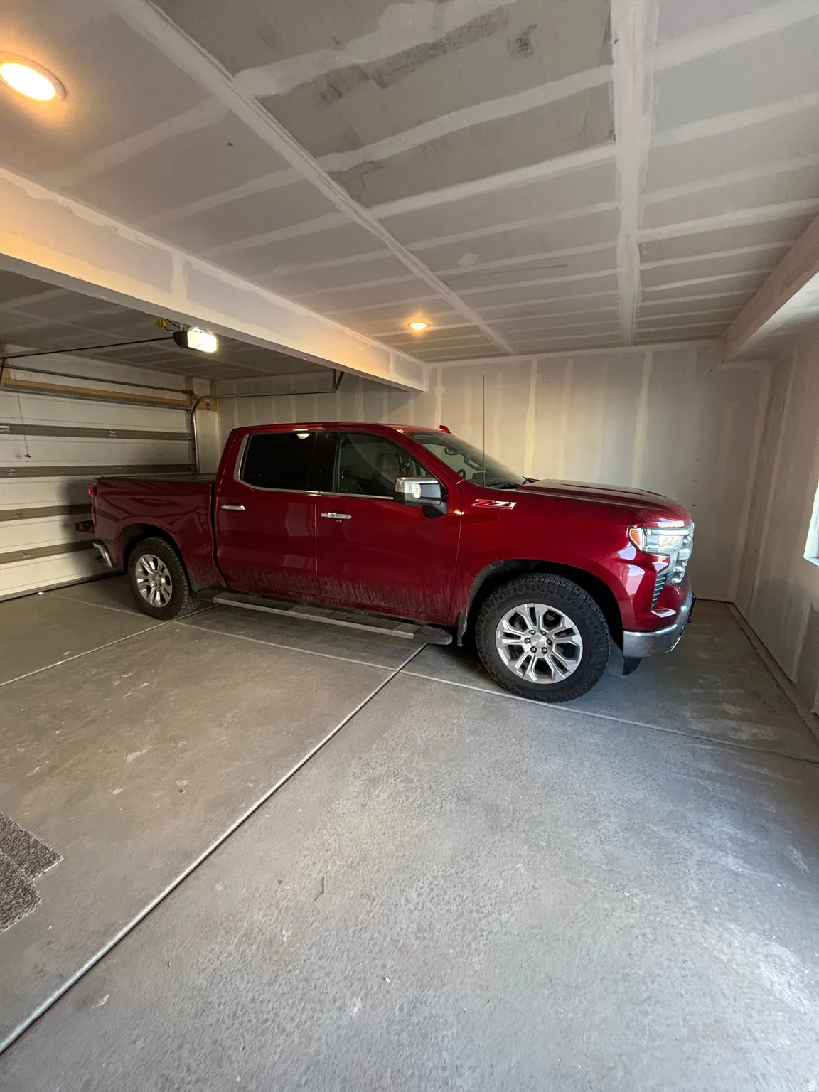 Garage space featuring a concrete floor, exposed ceiling beams, and recessed lighting