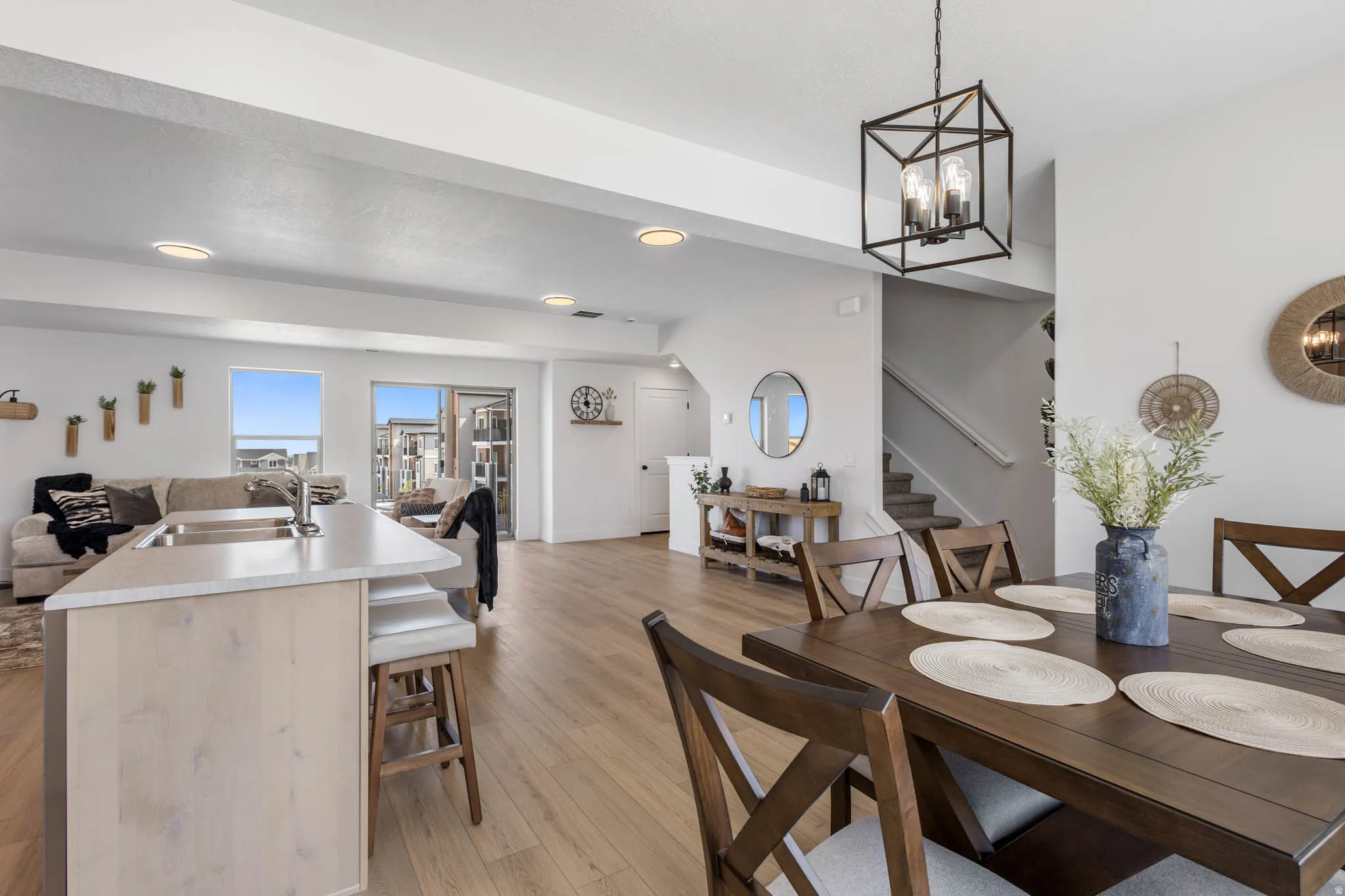 Open-concept living space featuring light wood-finish flooring, recessed lighting, and a modern kitchen island with an undermount sink