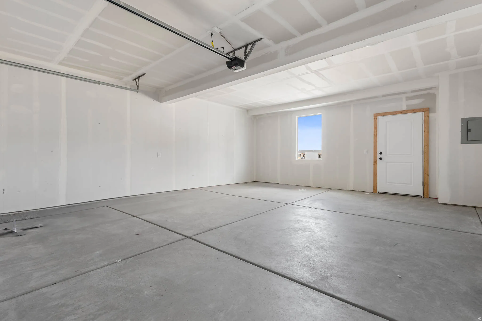 Spacious garage with concrete flooring, window for natural illumination, and an access door