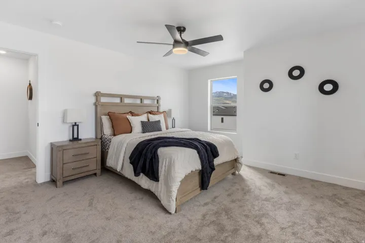 Carpeted bedroom featuring a ceiling fan with integrated lighting, a window with mountain scenery, and white walls