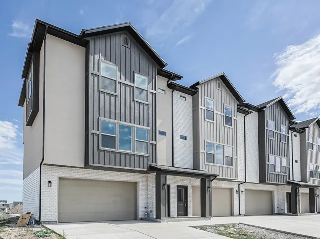Modern townhome facade featuring a neutral color palette, multiple large windows, and a two-car garage