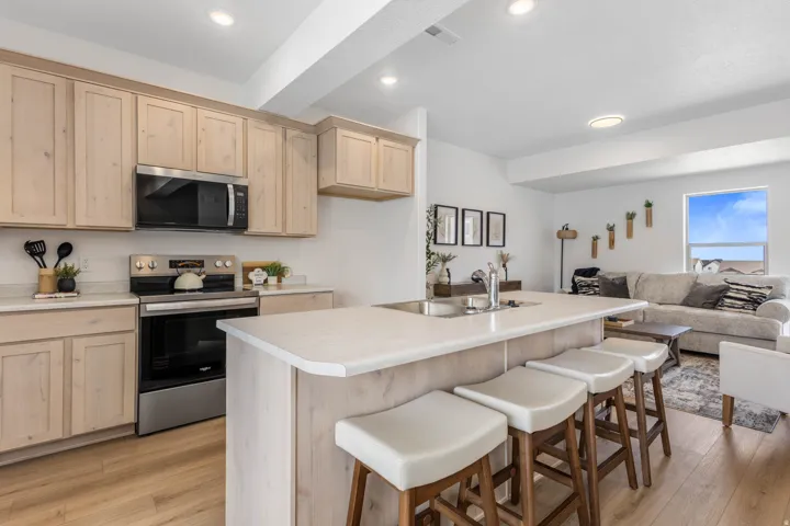 Kitchen featuring light wood-finish cabinetry, stainless steel appliances, a white countertop, recessed lighting, and wood-finish flooring