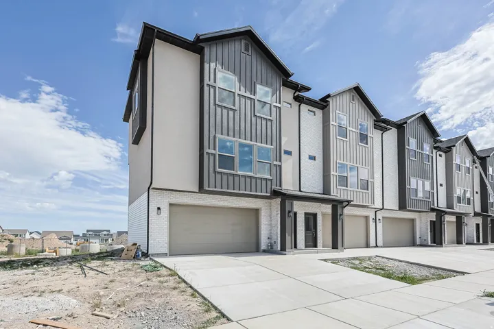 Modern townhome facade featuring a neutral color palette, multiple large windows, and a two-car garage