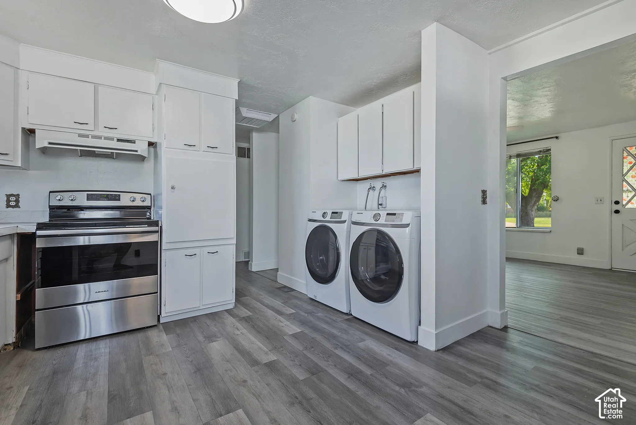 Kitchen area featuring white cabinetry, stainless steel range, and wood-finish flooring