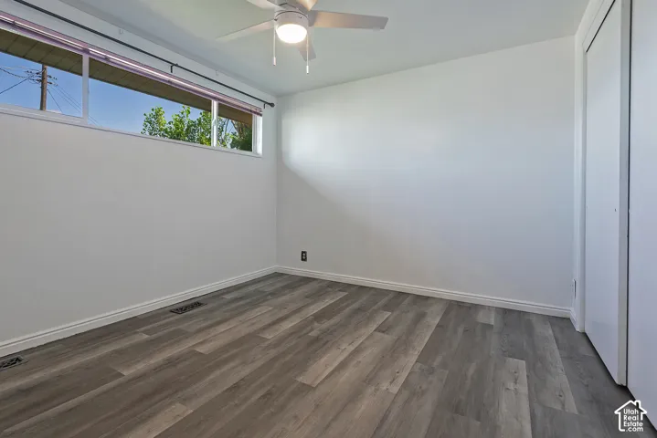 Room featuring wood-finish flooring, white walls, and a ceiling fan