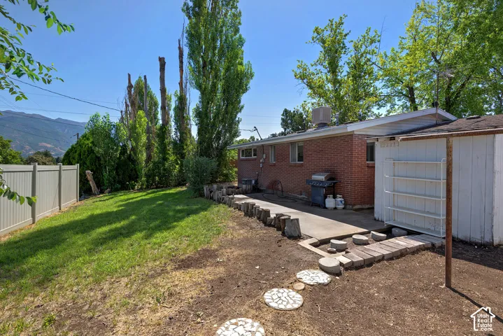 Expansive backyard featuring a manicured lawn, concrete patio, and a brick exterior building