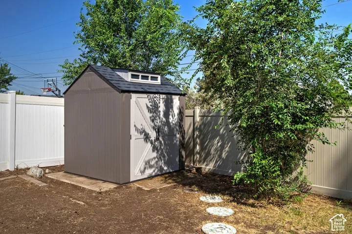 Freestanding storage shed with a dark shingled roof, white trim, and a built-in window feature