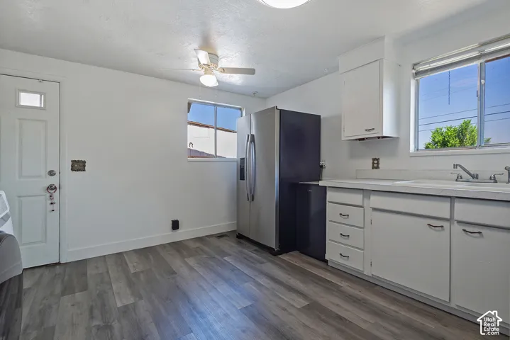 Kitchen featuring wood-finish flooring, white cabinetry, and a stainless steel refrigerator