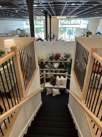 Hardwood staircase with black metal balusters and black carpeted treads