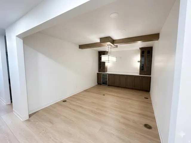 Recessed wall niche featuring a built-in wet bar with dark wood cabinetry, a beverage refrigerator, and a light-toned countertop