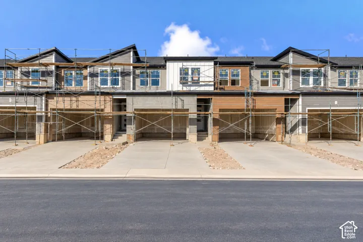 Multi-unit residential exterior featuring mixed-material siding, including horizontal lap and board-and-batten, gable rooflines, and individual concrete driveways