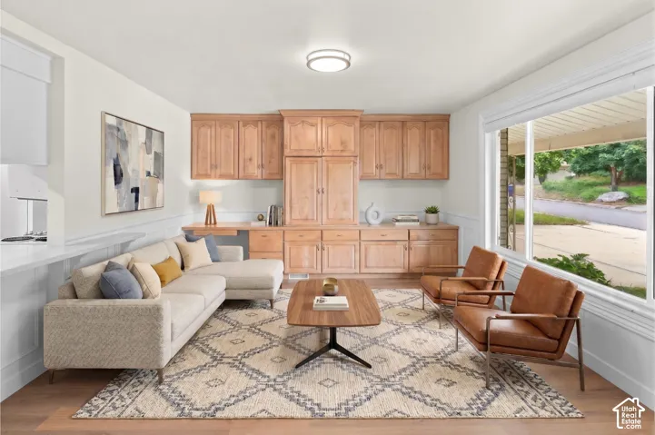 Built-in wood cabinetry with integrated desk space, wide window with white trim, white wainscoting, and wood-finish flooring