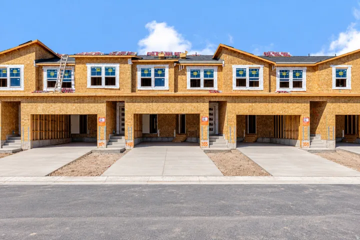 New construction townhome exteriors featuring multiple windows, attached garages, and concrete driveways