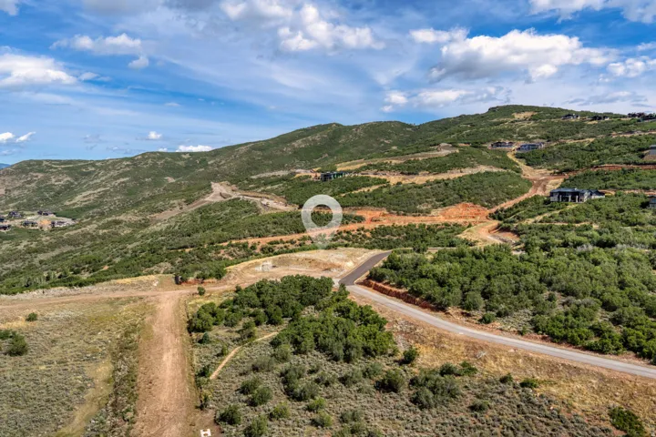 Hilly topography with visible ground clearings, natural vegetation, and paved roads