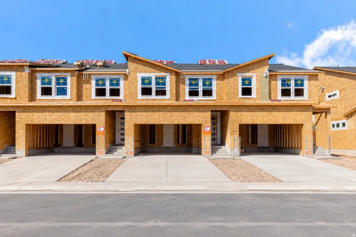New construction townhome framing with multiple windows, concrete driveways, and distinct entryways