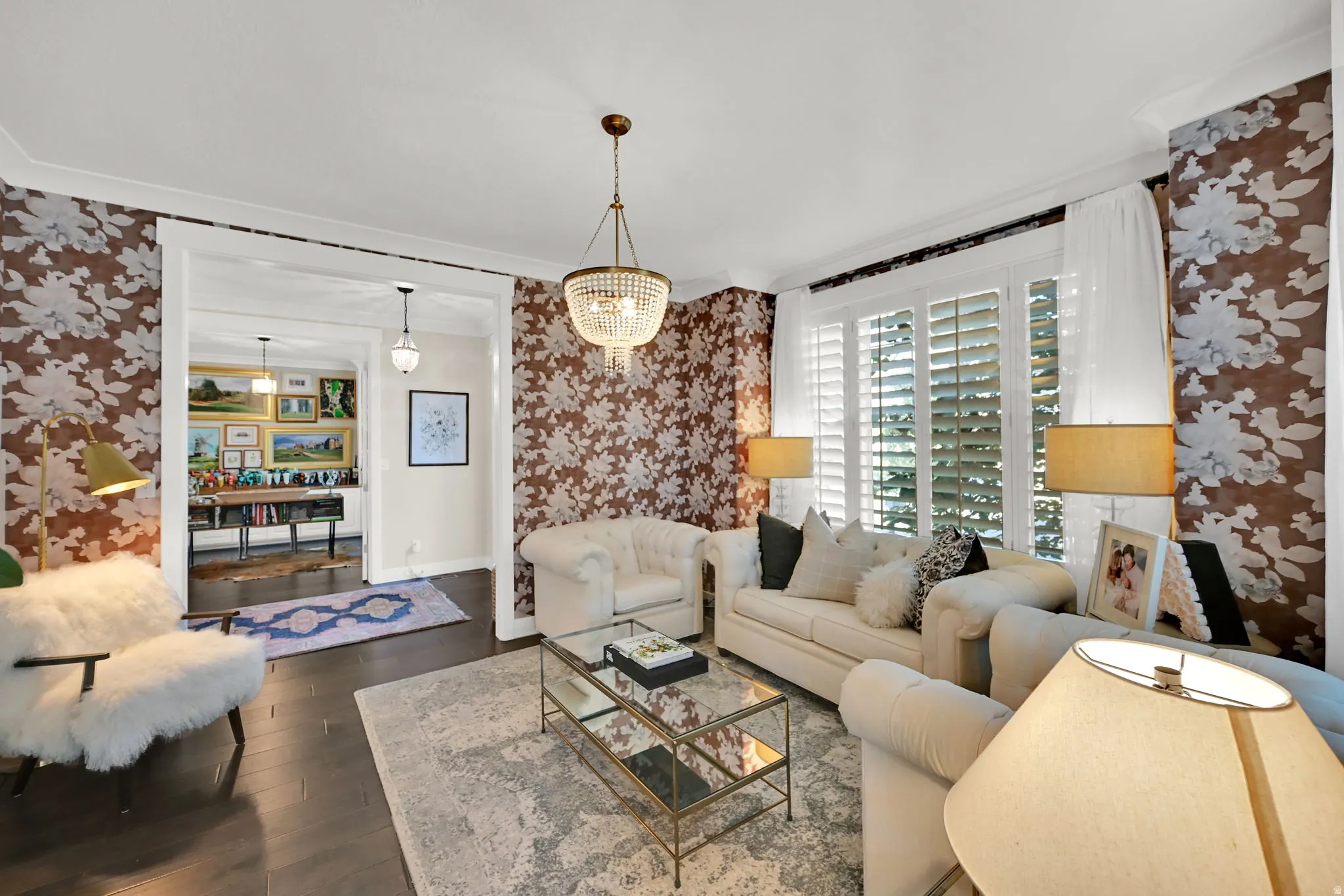 Living space featuring dark wood-finish flooring, patterned wallpaper, and white crown molding