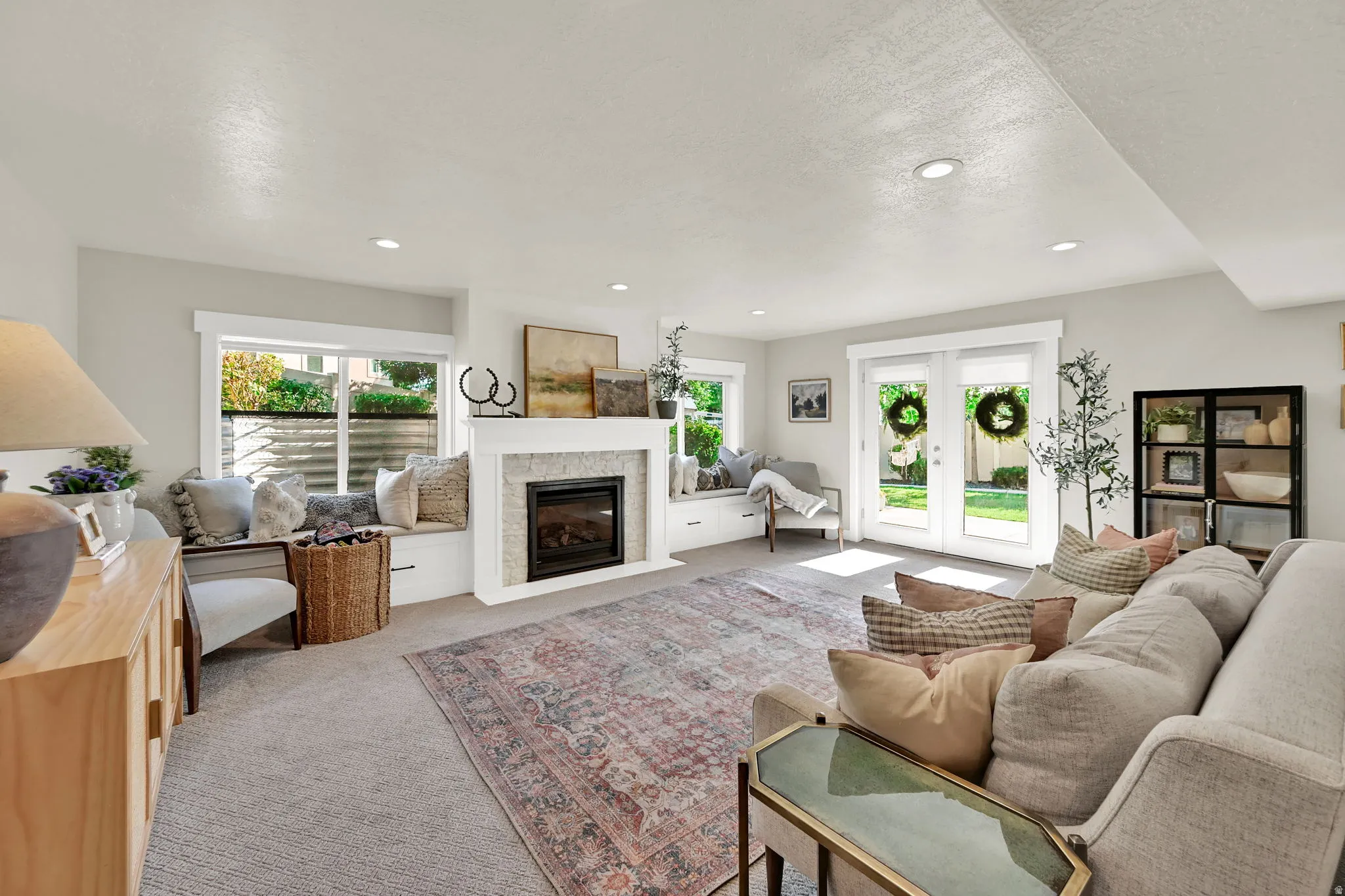 Living area featuring a fireplace with stone surround and white mantle, recessed lighting, and light-colored carpeting