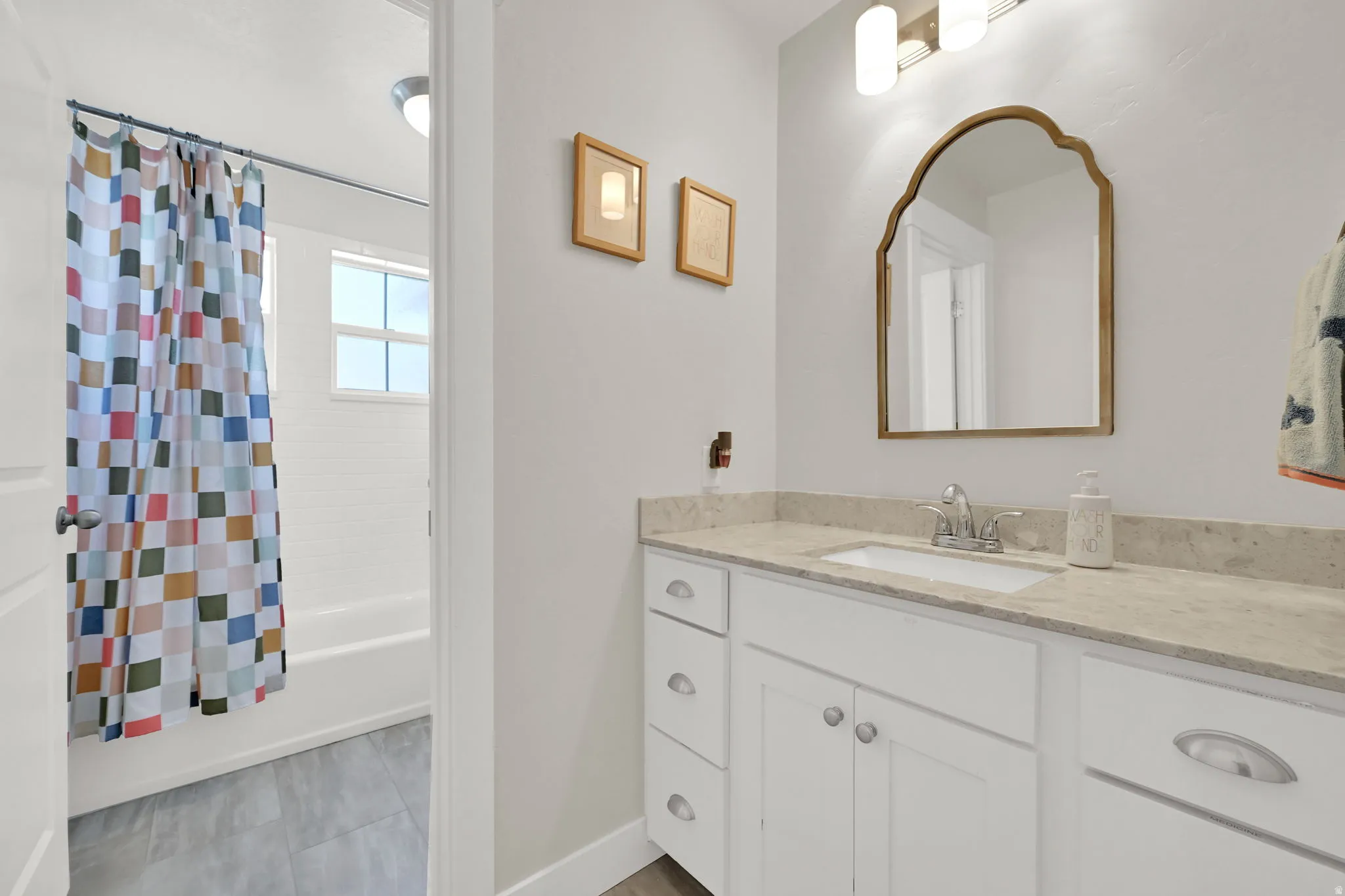 Bathroom featuring a white vanity with an undermount sink, a light-toned countertop, and a decorative mirror