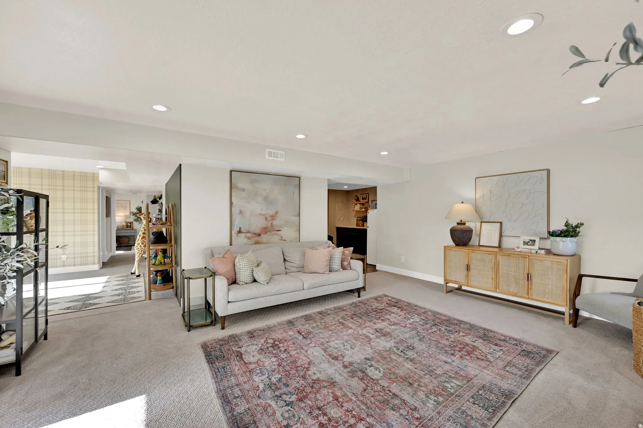 Spacious living area featuring neutral carpeting, recessed lighting, a built-in wall niche, and an open layout providing sightlines to additional areas