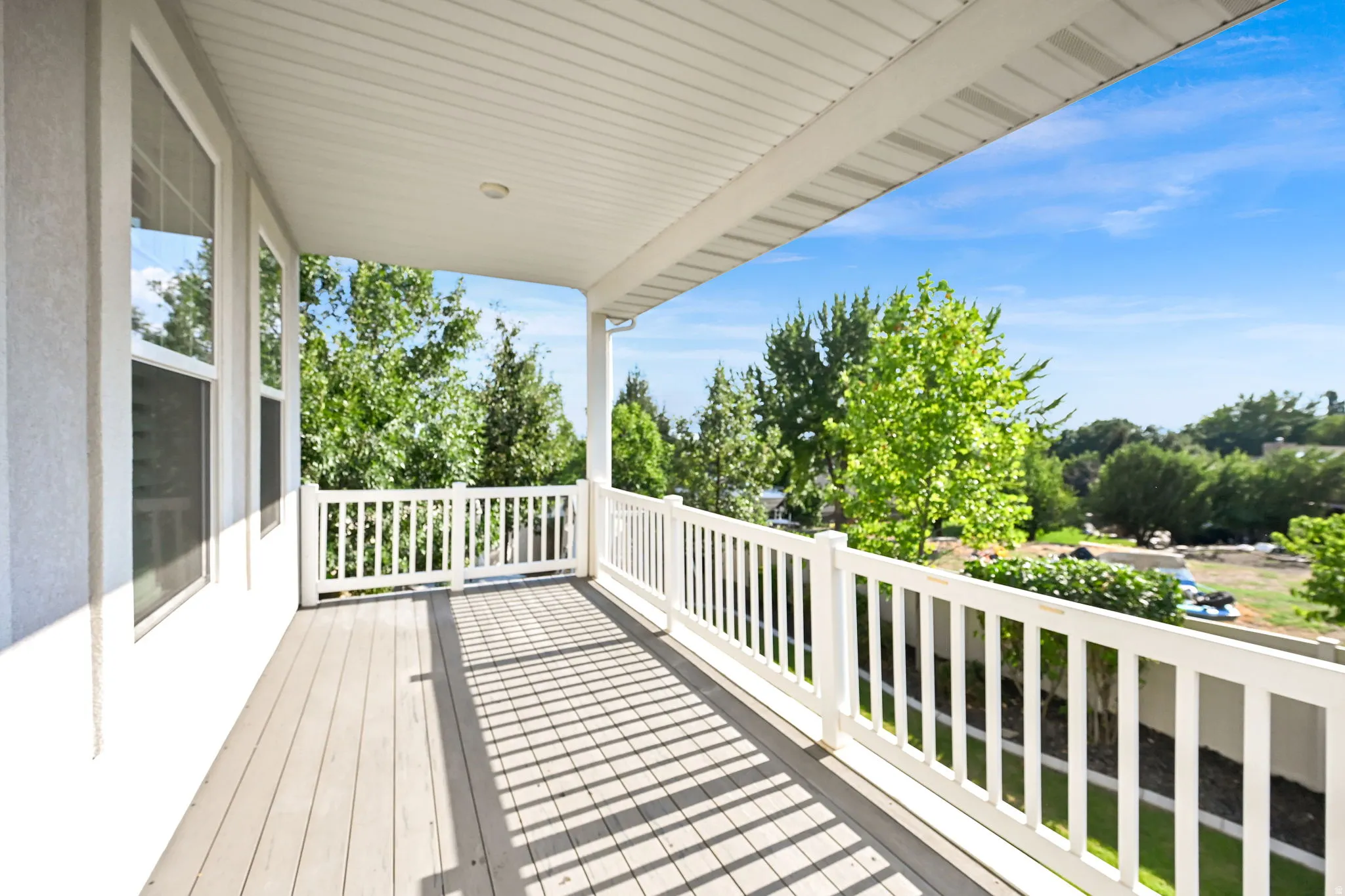 Covered balcony featuring wood-finish decking and white railing