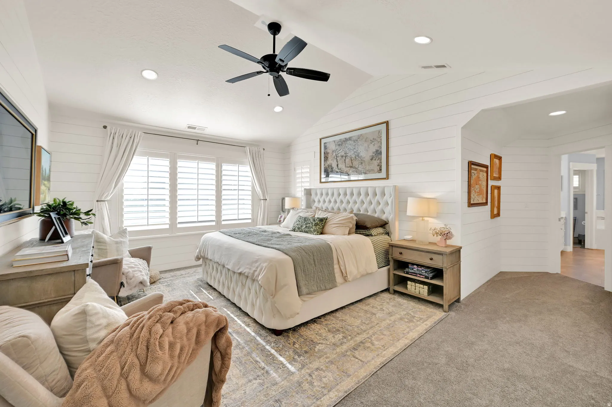 Primary Bedroom featuring white shiplap walls, vaulted ceiling with a black ceiling fan, recessed lighting, and an expansive window with white plantation shutters