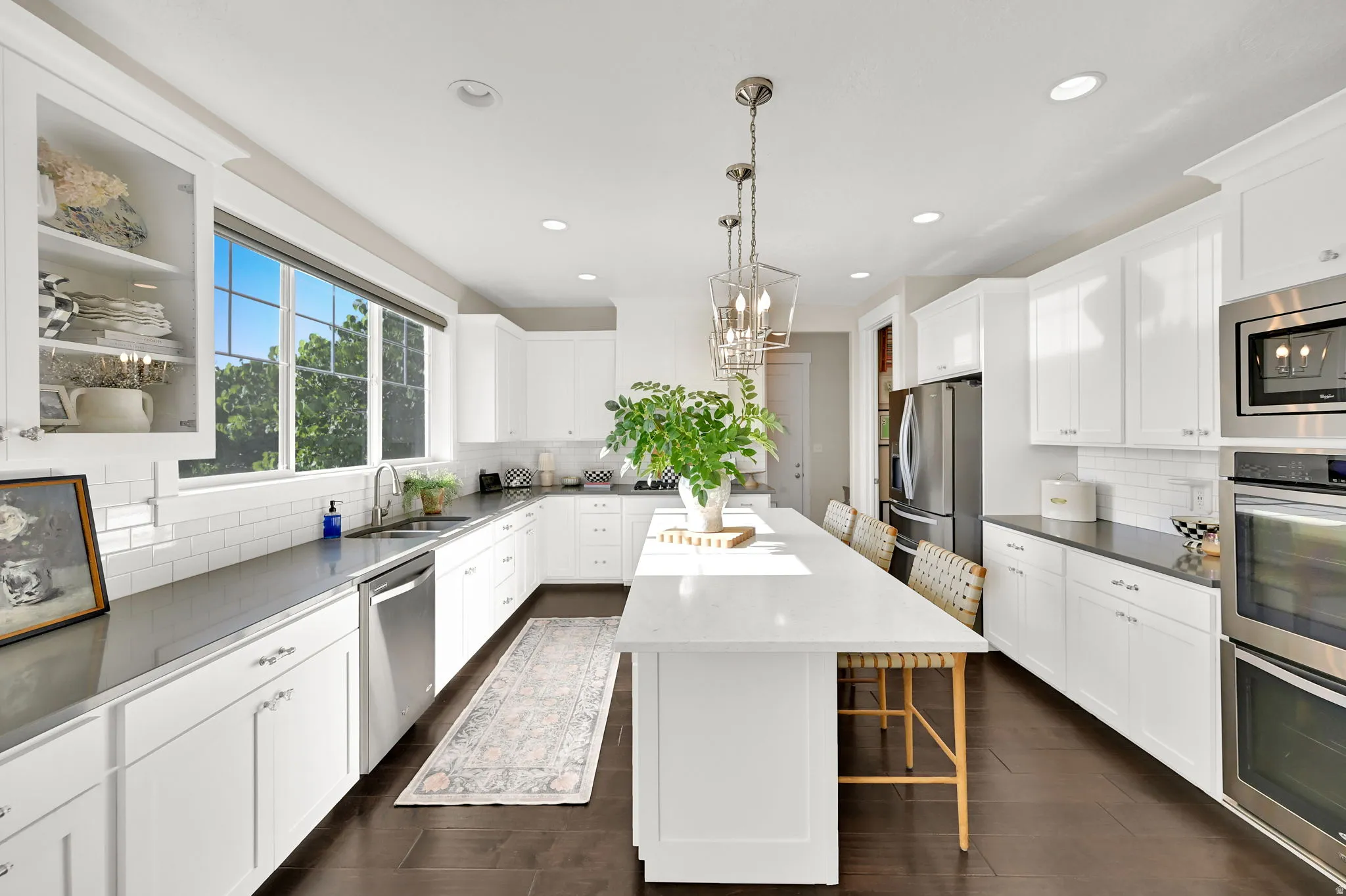 Bright kitchen featuring white cabinetry, dark countertops, and stainless steel appliances