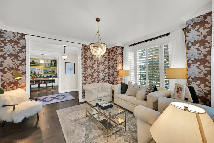 Living space featuring dark wood-finish flooring, patterned wallpaper, and white crown molding