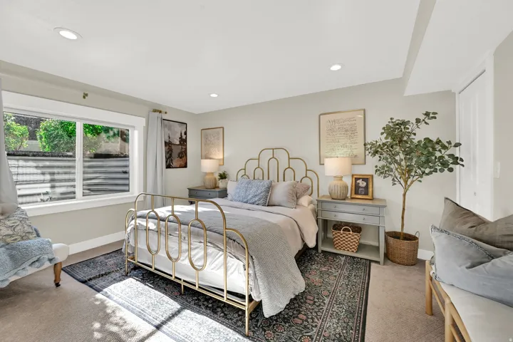 Carpeted bedroom featuring a large window with white trim, recessed lighting, and a white paneled door