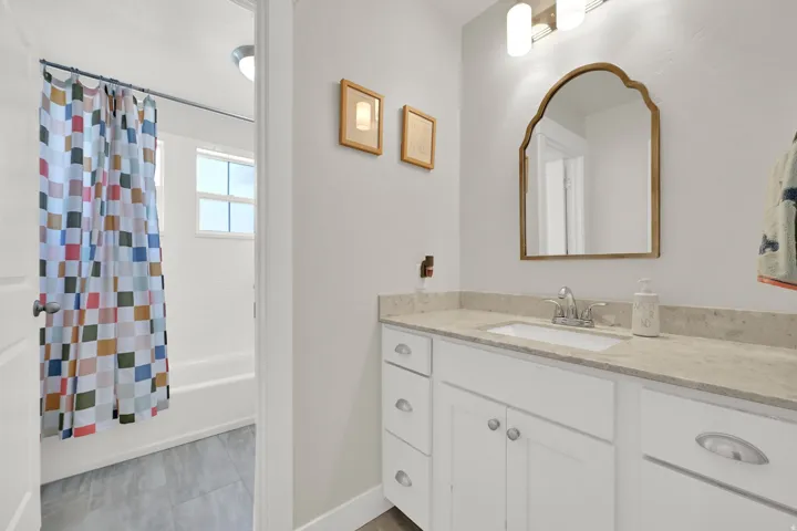 Bathroom featuring a white vanity with an undermount sink, a light-toned countertop, and a decorative mirror