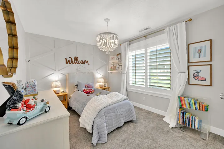 Spacious room featuring a decorative accent wall, white plantation shutters, and a crystal chandelier